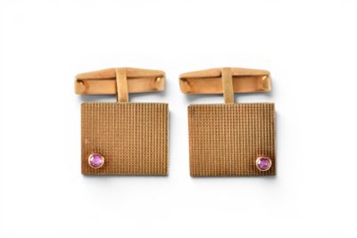 a pair of brown cufflinks with pink stones on them