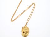 un collier en or avec un pendentif en forme de visage, monté sur une chaîne