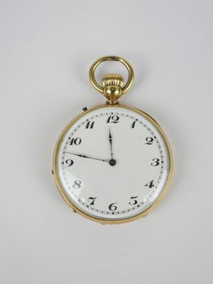 une montre de poche en or avec un cadran blanc sur une surface blanche