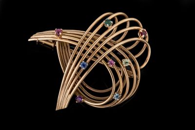 un gros plan sur une broche en or sertie de pierres multicolores