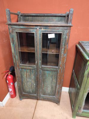 une vieille armoire en bois avec des portes vitrées et un extincteur