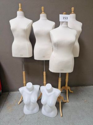 Trois mannequins blancs sont exposés devant un mur