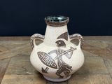 a white vase with a design on it sitting on a table