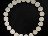 a close up of a necklace made of silver coins on a black background