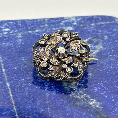 an image of a diamond and silver broochle on a blue marble surface