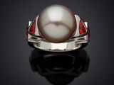 a close up of a pearl and ruby ring on a black surface