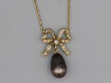 a close up of a necklace with a bow on it