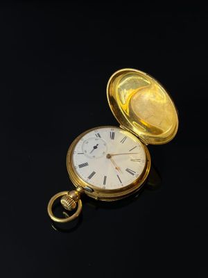 pocket watch on a black surface with a gold case and roman numerals