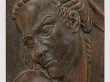 une image représentant une plaque en bois sur laquelle figure le buste d'une femme