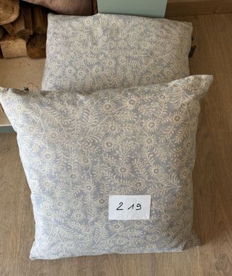 deux oreillers, avec une étiquette de prix, posés sur un plancher en bois
