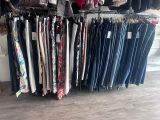 beaucoup de vêtements suspendus à une étagère dans une pièce