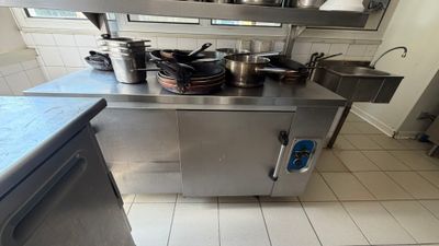a large stainless steel kitchen with many pots and pans on the counter