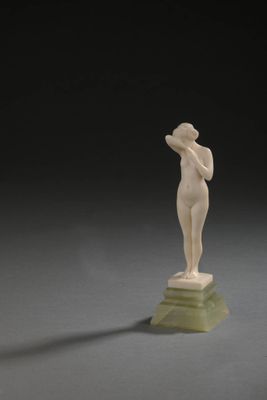 statue d'une femme debout sur un socle vert, sur fond noir
