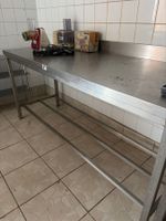 Une table inox avec dosseret et entre jambe.