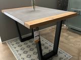La table est en béton et en acier, avec un plateau en bois.