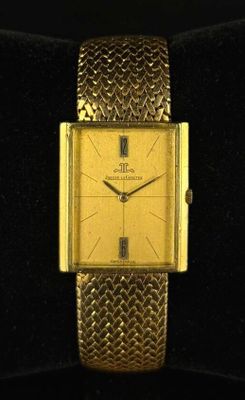 une image représentant une montre en or posée sur une surface noire