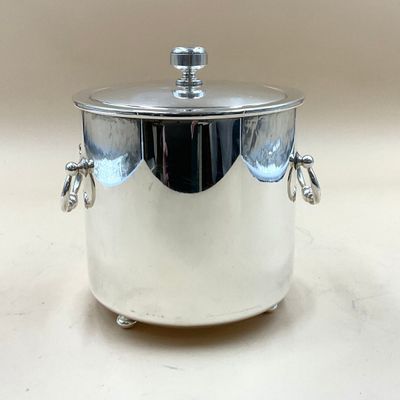 une casserole en argent avec un couvercle, posée sur une table blanche