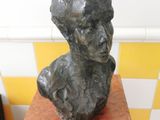 a statue of a man sitting on a wooden pedestal