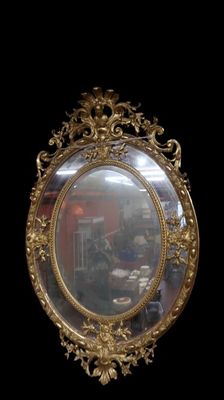 a mirror with a gold frame on a black wall