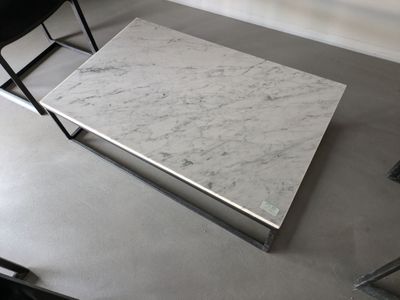 une table en marbre blanc avec une chaise noire en arrière-plan
