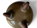 an overhead view of a brown vase with three acorns on it