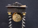 a clock that is on a stand with a rope around it