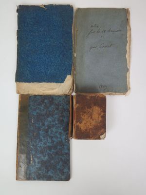 several old books are stacked on top of each other on a white surface