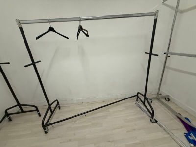 a rack with clothes hanging on it in the corner of a room