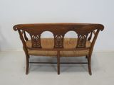 a wooden bench that has a wicker seat on it