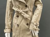 an image of a mannequin wearing a beige trench coat and black tights