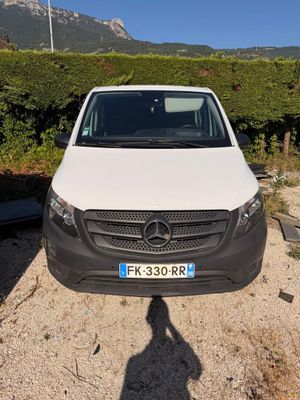 une camionnette blanche garée sur un parking, avec les montagnes en arrière-plan
