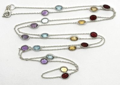 quatre pierres de couleurs différentes montées sur une chaîne en argent, posées sur un fond blanc