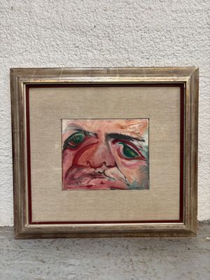 painting of a man ' s face in a gold frame on a white wall