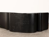 a close up of a black curved table on a concrete floor