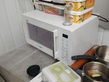un four à micro-ondes posé sur un plan de travail sur lequel se trouvent des casseroles et des poêles