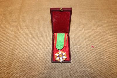 une boîte rouge ornée d'un ruban vert et d'une médaille en or