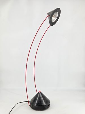 a black table lamp with a red cord and a white background
