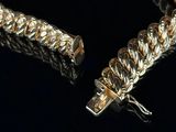 two gold bracelets on a black background with a cross in the middle