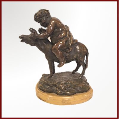 statue en bronze représentant un garçon à dos d'âne, tenant un oiseau dans la main