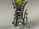 a green vase that is sitting on a metal stand