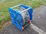 a blue reel sitting on the ground next to a solar panel