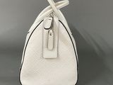 a close up of a white purse on a gray surface