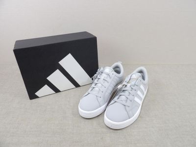 a pair of white adidas sneakers in front of a black box