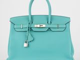 un sac à main en cuir bleu muni d'un cadenas sur la poignée