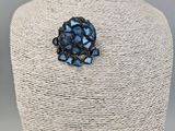 a close up of a blue broochle on a mannequin