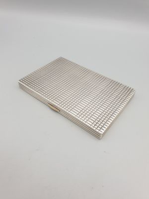 une image représentant un étui à cigarettes argenté posé sur une surface blanche