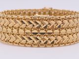 a close up of a gold bracelet on a white surface
