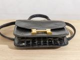 a black purse with a gold handle sitting on top of a wooden table