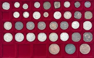 un assortiment d'objets en argent et de pièces d'argent présentés dans une vitrine rouge