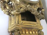 a gold clock that is on the wall of a room